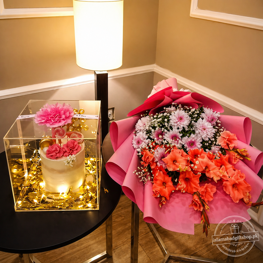 Luxury gift set with a pink floral bouquet and a mini decorated cake inside a clear LED-lit acrylic box