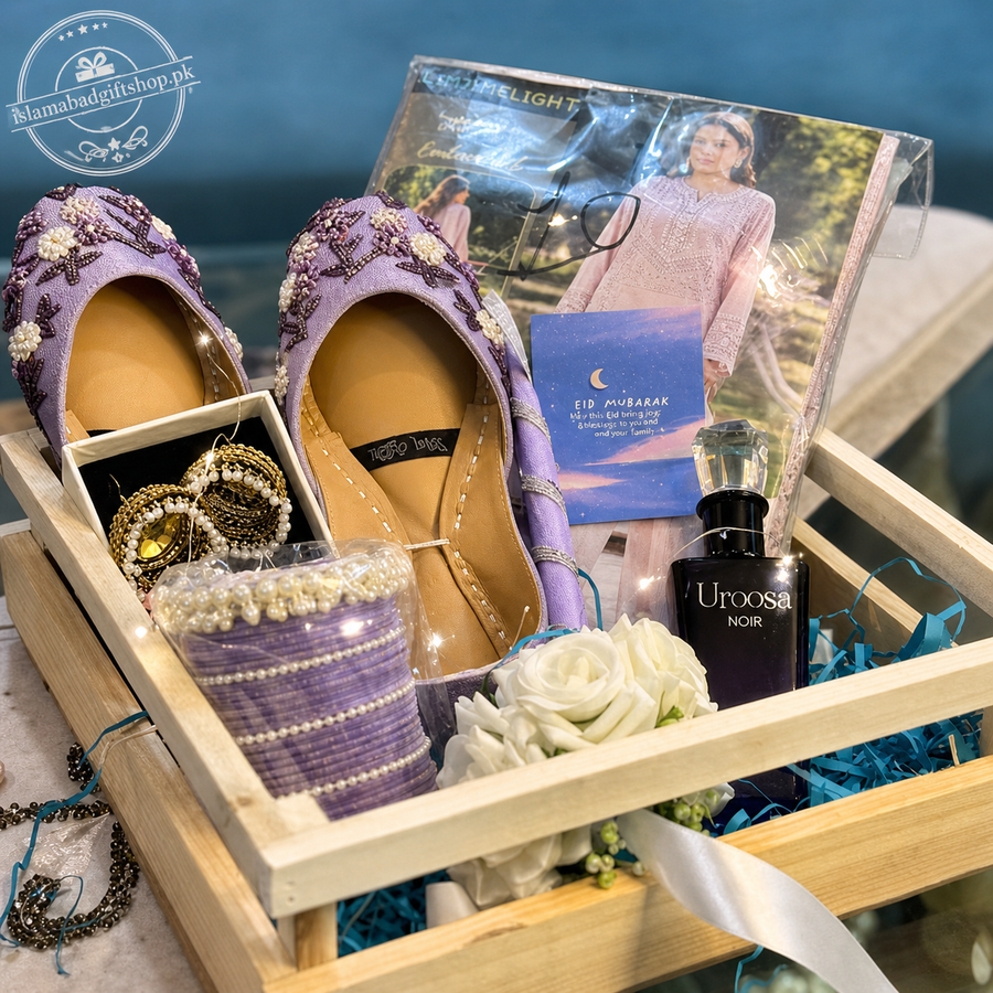 Gift set with purple shoes, jewelry, and a bottle of Uroosa Noir perfume in a wooden box.