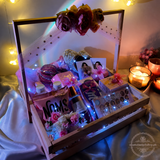 Decorative box with LED lights, flowers, and photos on a soft surface.