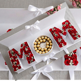 A sophisticated, open white gift box set that spells out "MOM" in three sections.