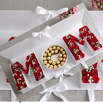 A sophisticated, open white gift box set that spells out "MOM" in three sections.
