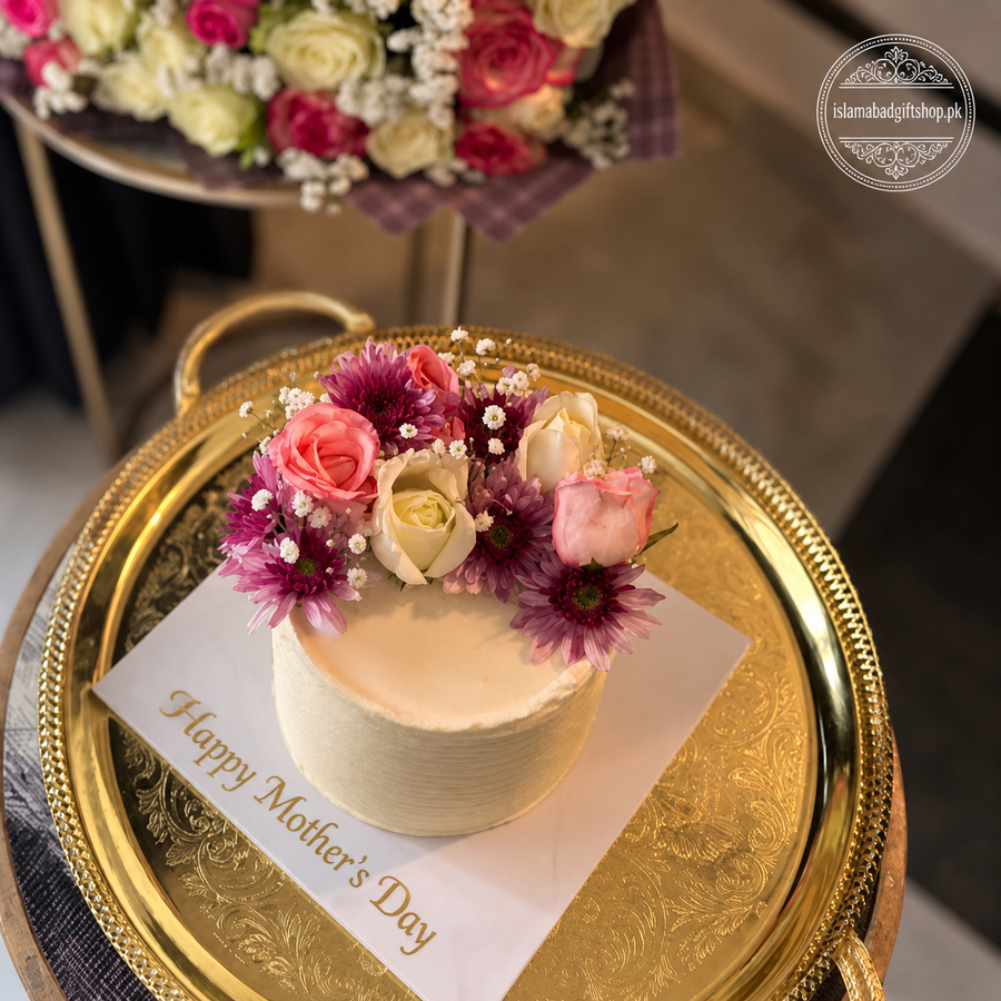 Decorative cake with flowers on a gold tray with 'Happy Mother's Day' card, surrounded by more floral arrangements.