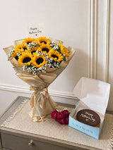 appy Mother’s Day sunflower bouquet with golden wrapping and chocolate cake in a gift box.