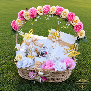 Luxury floral gift basket with pink and cream roses, golden butterflies, wrapped dresses, perfume, chocolates